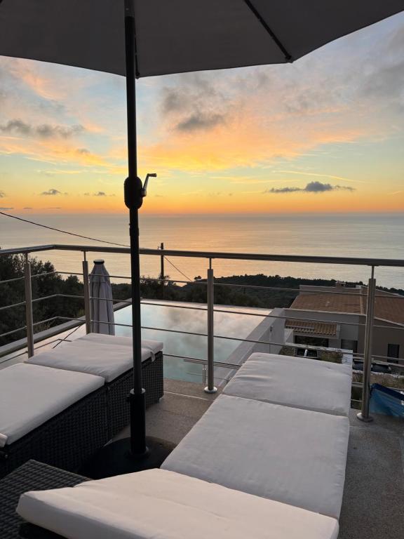 a balcony with a view of the ocean at sunset at Villa Skalia Lefkada in Athani