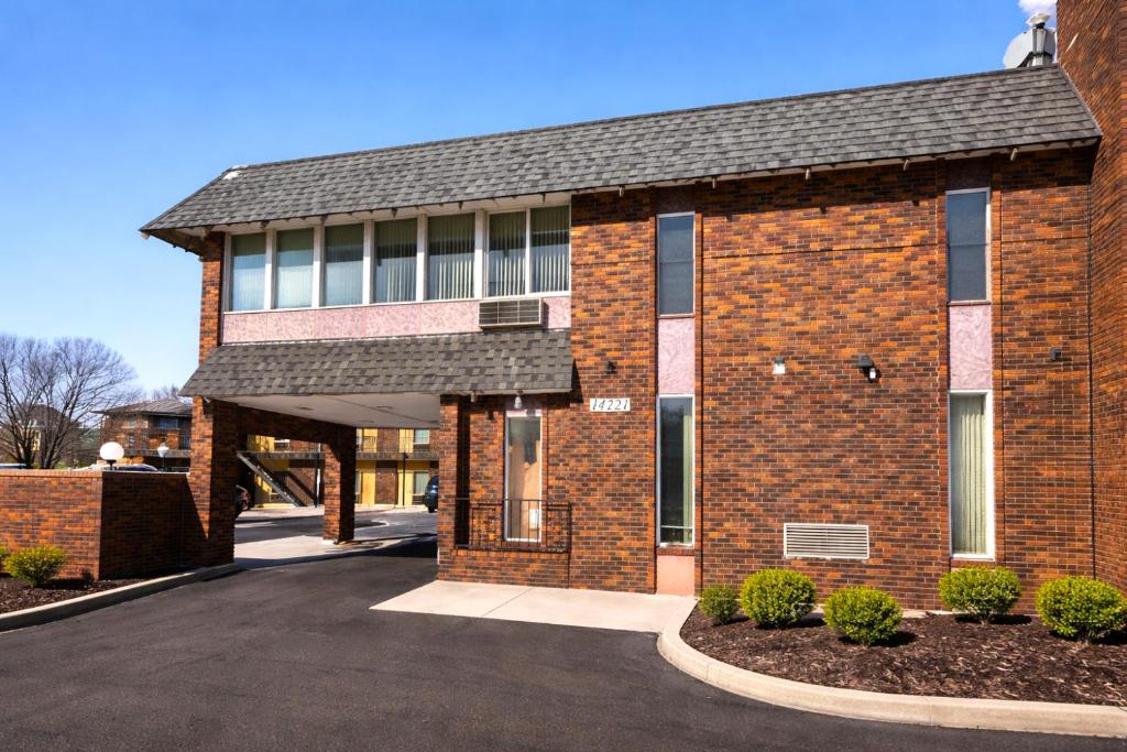 a brick building with a driveway in front of it at The Queen B Motel, Detroit-Warren in Warren