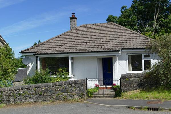 a small white house with a stone wall at Correay Cottage in Salen