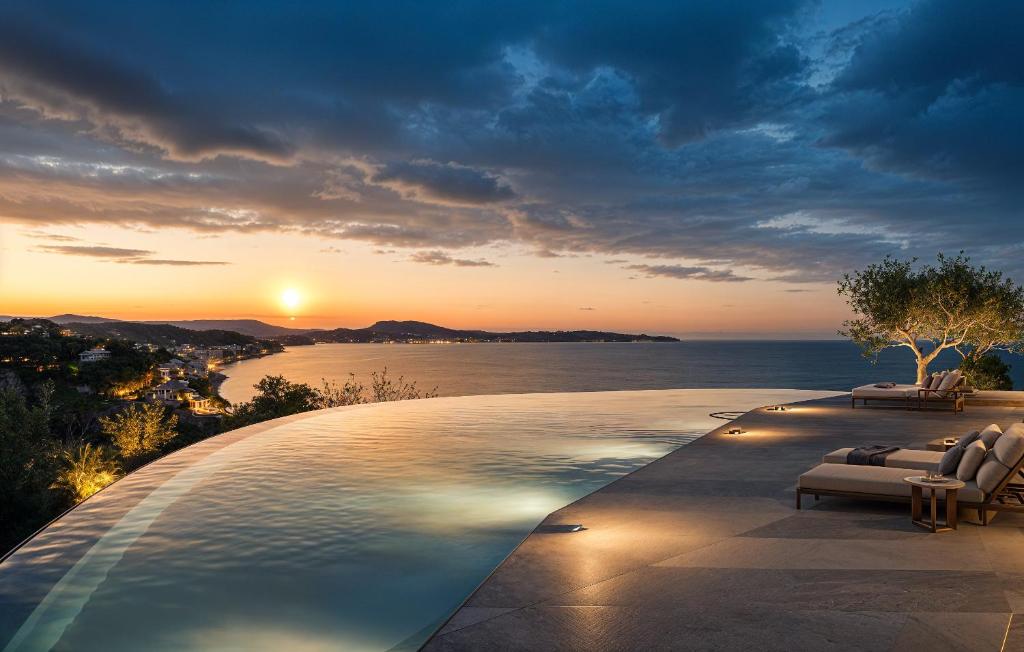 a infinity pool with a view of the ocean at sunset at Ionian Hill Hotel in Argassi