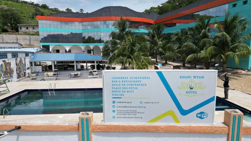 a sign next to a swimming pool in front of a building at Hôtel Kolou Wyam in Tcharé