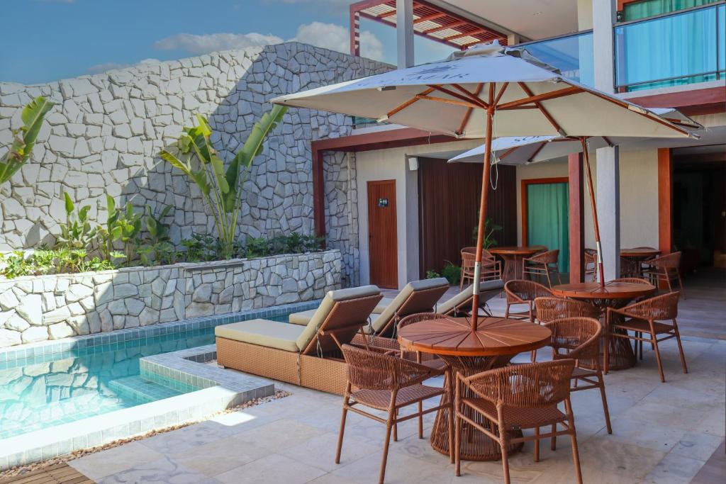 eine Terrasse mit Tischen, Stühlen und einem Sonnenschirm in der Unterkunft Villa Sol e Mar in Maragogi