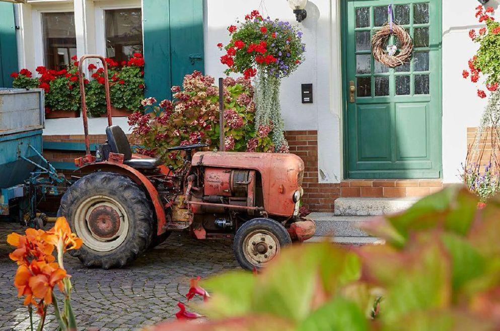 an old tractor parked outside of a house with flowers at Weingut Stefan Meyer in Rhodt unter Rietburg