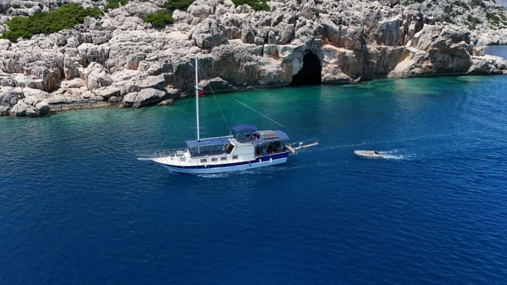 a boat in the water next to a cave at YourTourKey Gulet Accommodation in Güvercin Adası