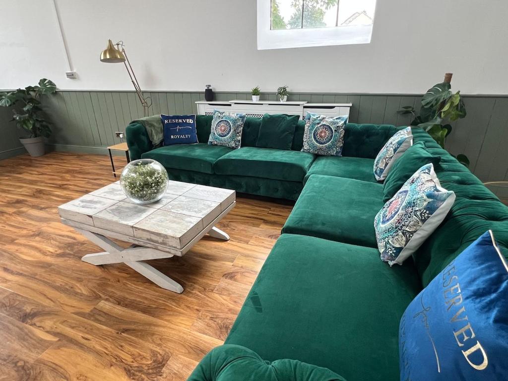 a living room with a green couch and a table at The Cotswold Wellhouse in Tetbury