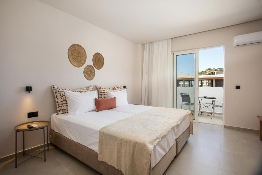 a bedroom with a large white bed and a balcony at Pado Living in Faliraki