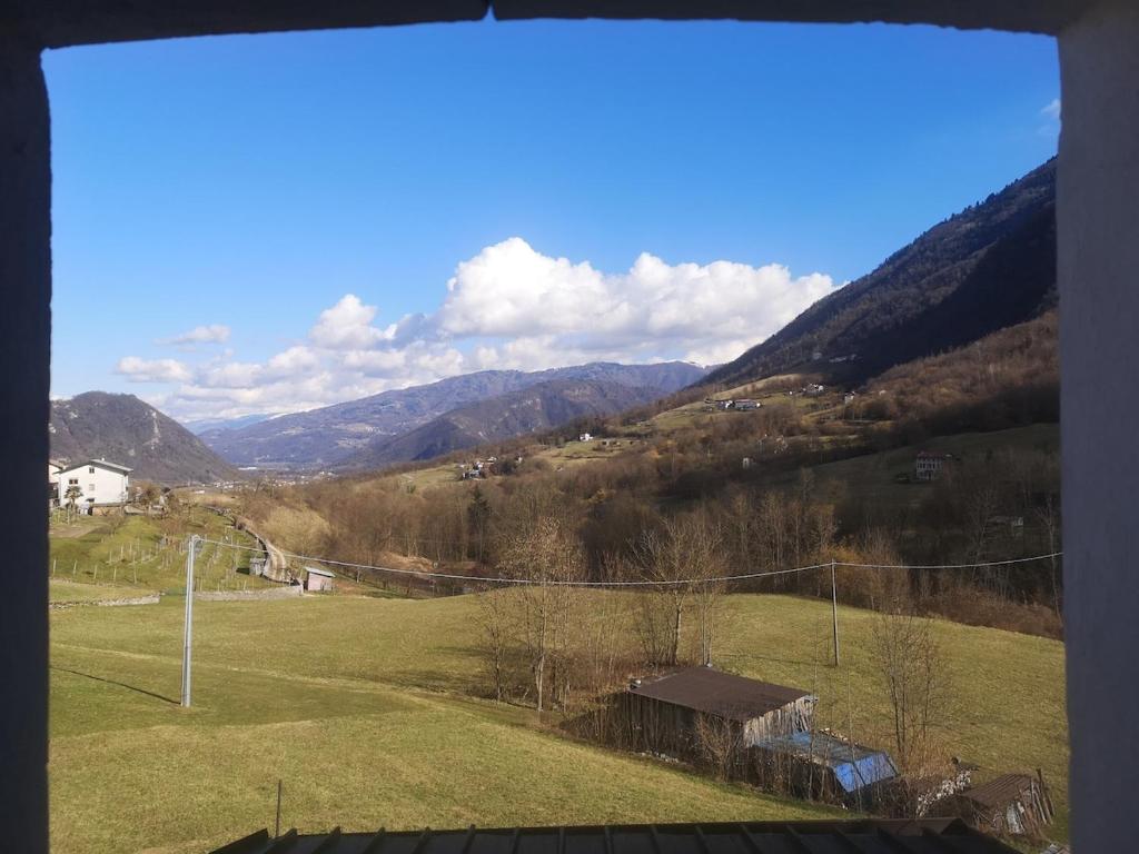 a view from a window of a field and mountains at Casa vacanze Feltre in Feltre
