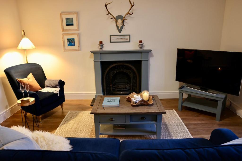 a living room with a blue couch and a fireplace at The Coastal Haven, Broughty Ferry in Dundee