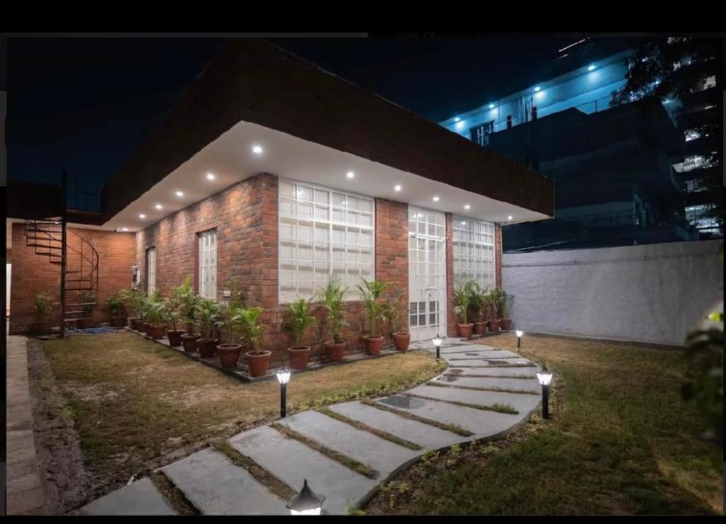 a building with potted plants in front of it at night at The carmine house-Private 4 BHk luxury retreat in sector 132, Noida in Noida