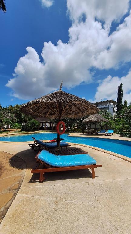 a table with an umbrella next to a pool at Malindi Sunset Apartments in Malindi