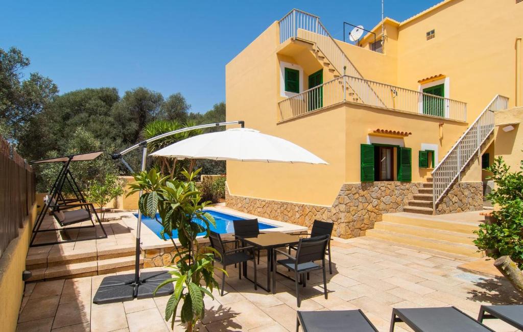 a patio with a table and an umbrella and a house at Calamari 7 in Portocolom