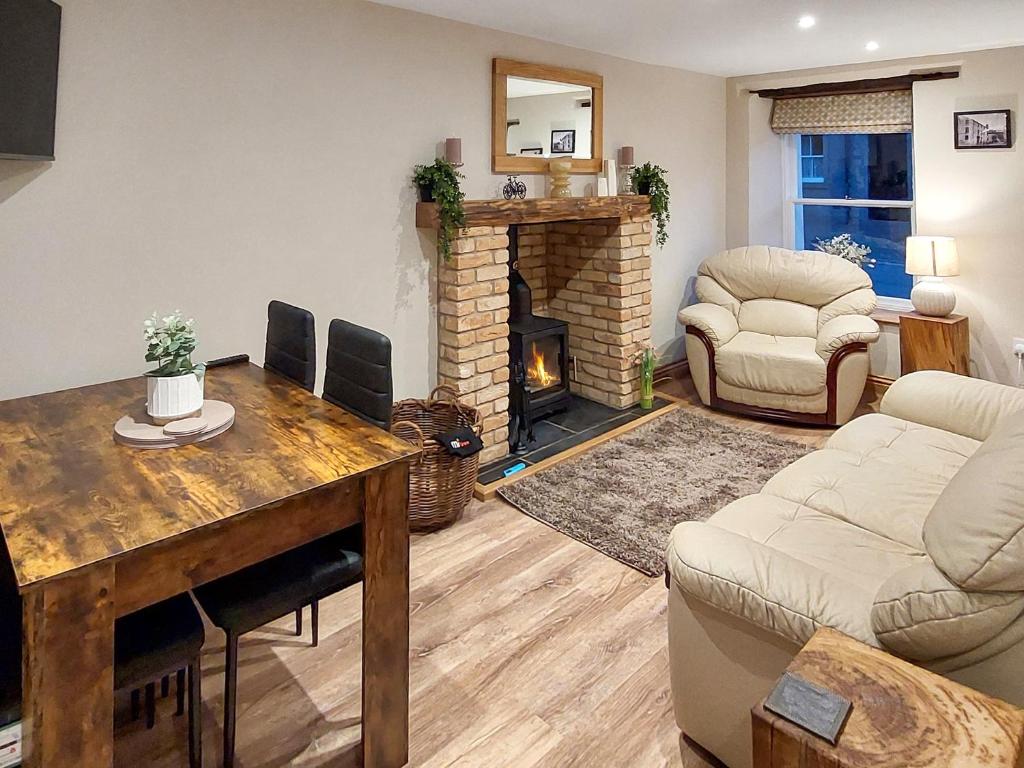 a living room with a table and a fireplace at 13 Doomgate Cottage - Uk45056 in Appleby