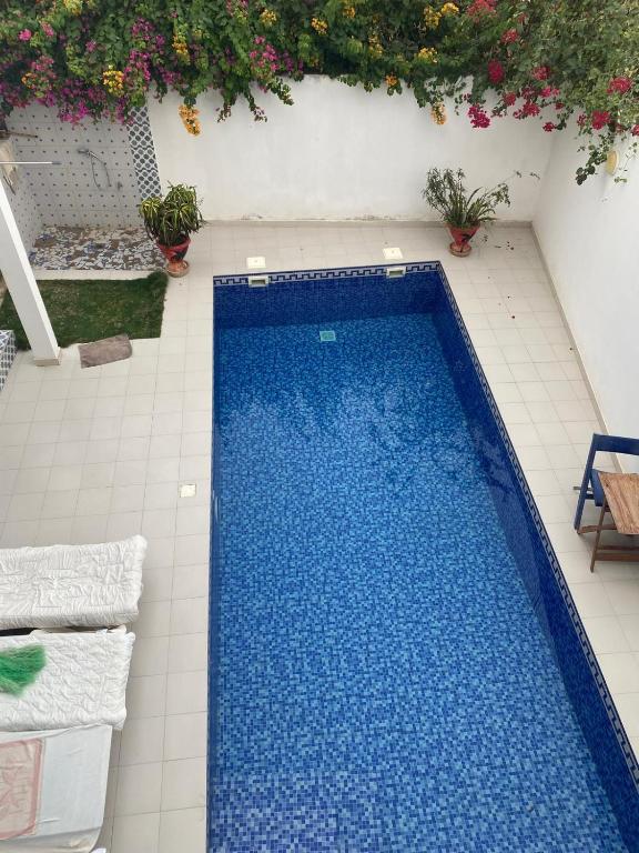 a blue swimming pool on a tile floor with flowers at keur Baye fall fall saly in Sali Nianiaral