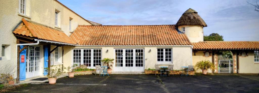 an old house with a large building with a roof at Hotel La Chaumière in Saint-Jean-de-Monts