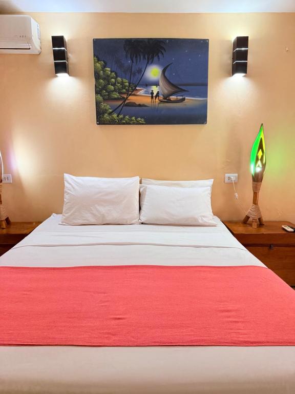 a bed with a red blanket and a painting on the wall at Rede Andrade Calamarina in Jericoacoara