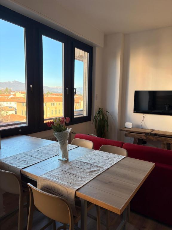 a dining room with a table and chairs and windows at Appartamento con vista su Brunate in Olgiate Comasco
