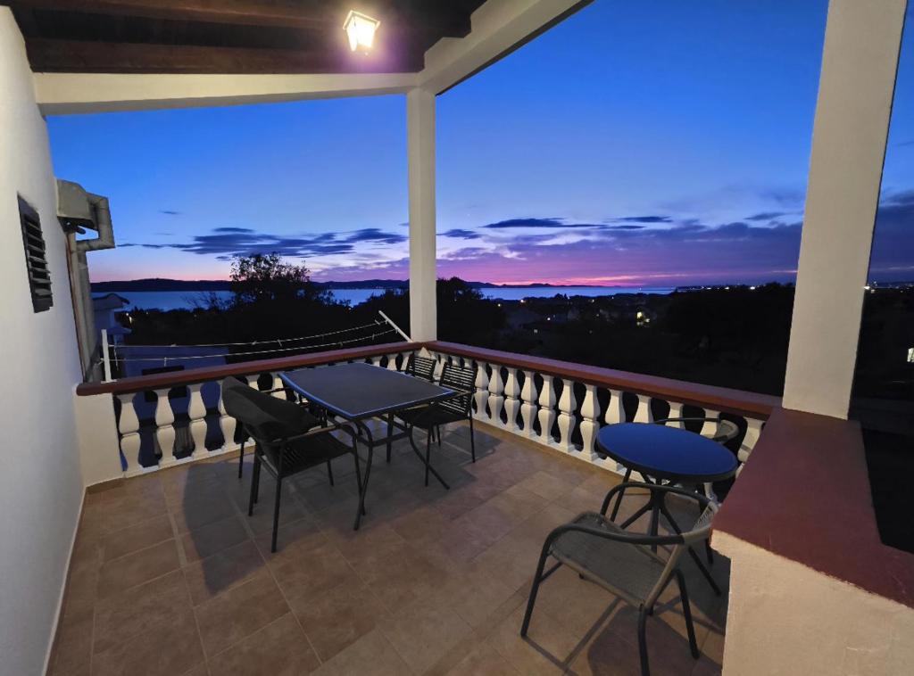a balcony with tables and chairs at night at Apartmani Vera in Bibinje