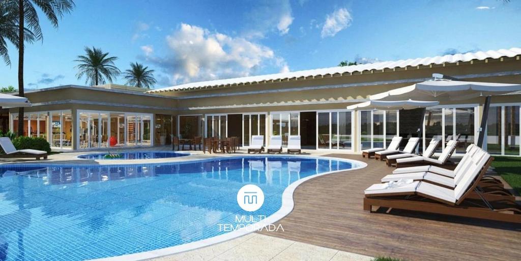 a pool with chairs and umbrellas next to a house at Rosa Internacional - Surfland in Praia do Rosa
