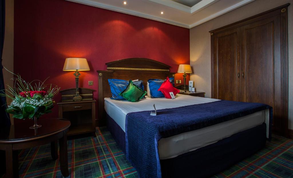 a bedroom with a bed with blue sheets and colorful pillows at Merit Lefkosa Hotel & Casino in North Nicosia