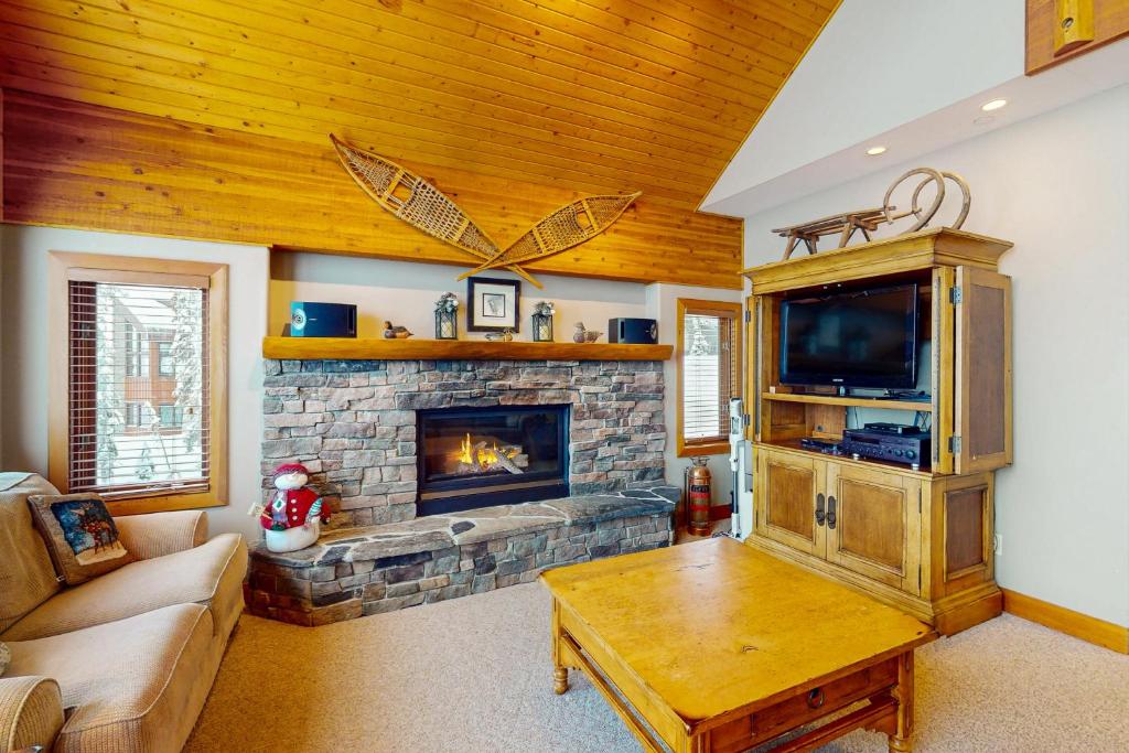 a living room with a fireplace and a tv at Coyote Creek Chalet in Big White