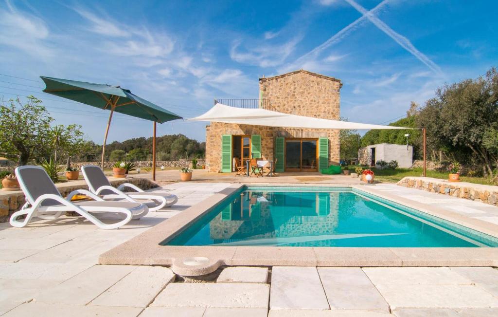 a pool with chairs and an umbrella and a house at Son Frare in Artá
