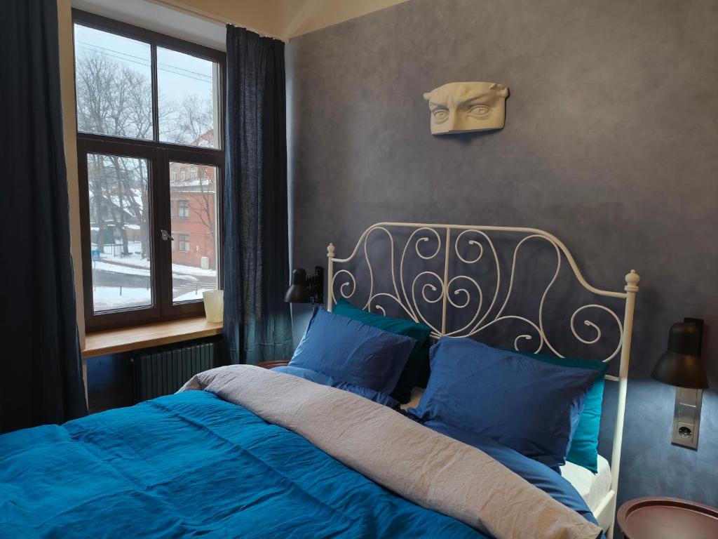 a bedroom with a bed with blue sheets and a window at Red Doors Apartament 23 Free Parking in Riga