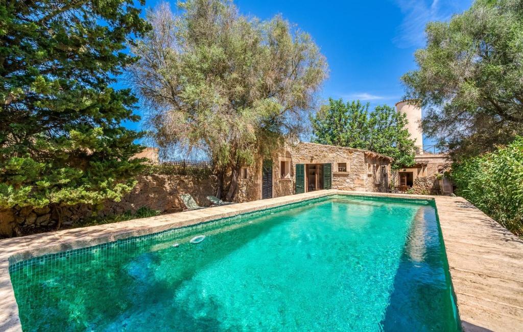 a swimming pool in front of a house with trees at Moli Den Guixo in Artá