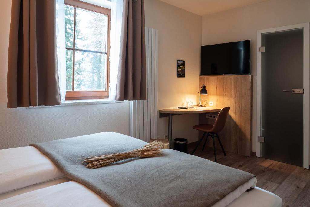 a bedroom with a bed and a desk and a window at Hotel in der Mühle in Werdau