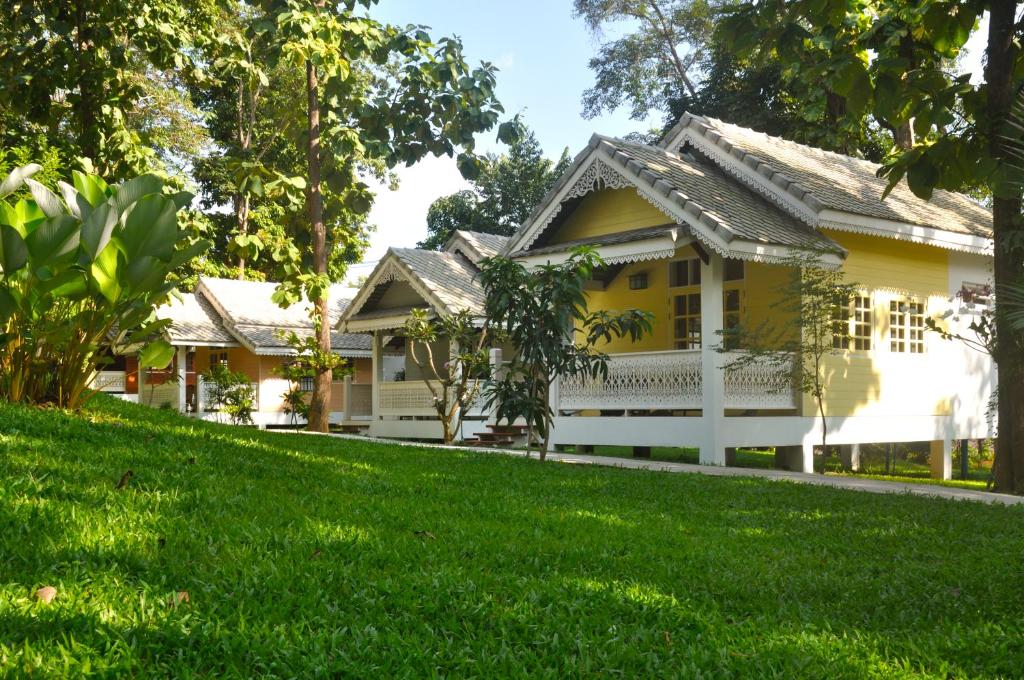 una casa con un césped verde delante de ella en Monoceros Resort, en Mae Rim