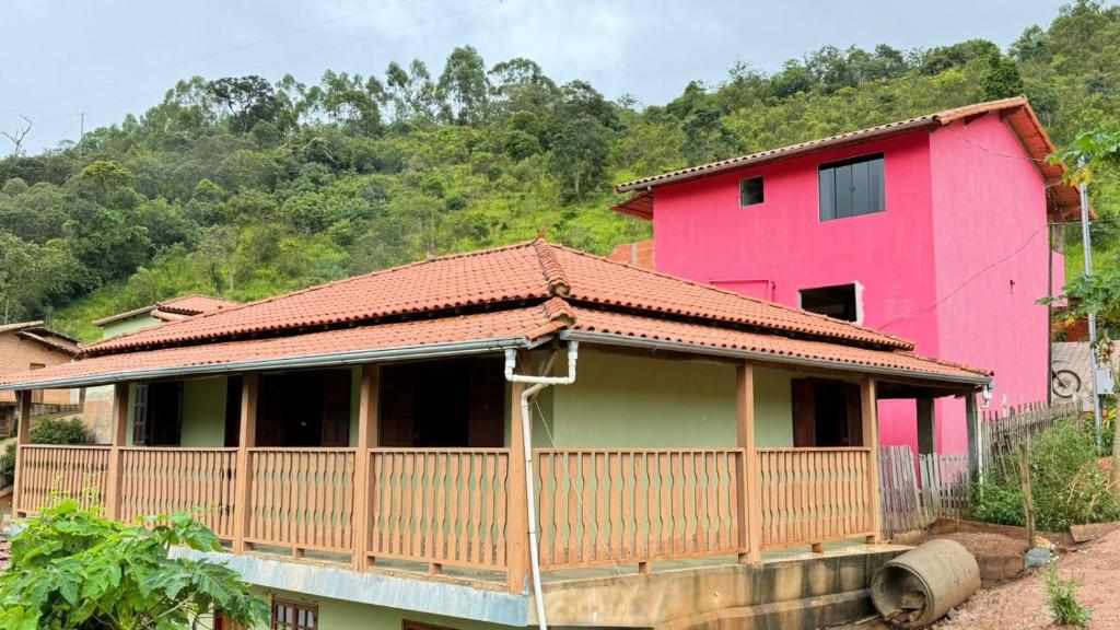 a pink house with a fence in front of it at Cantinho da Nara em Ibitipoca in Conceição da Ibitipoca