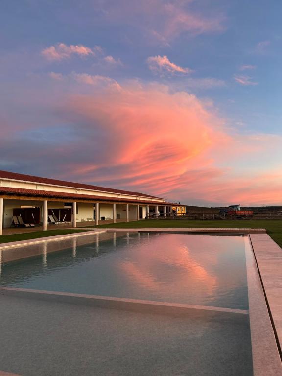 a swimming pool in front of a building with a sunset at Herdade do Serra in Ervidel