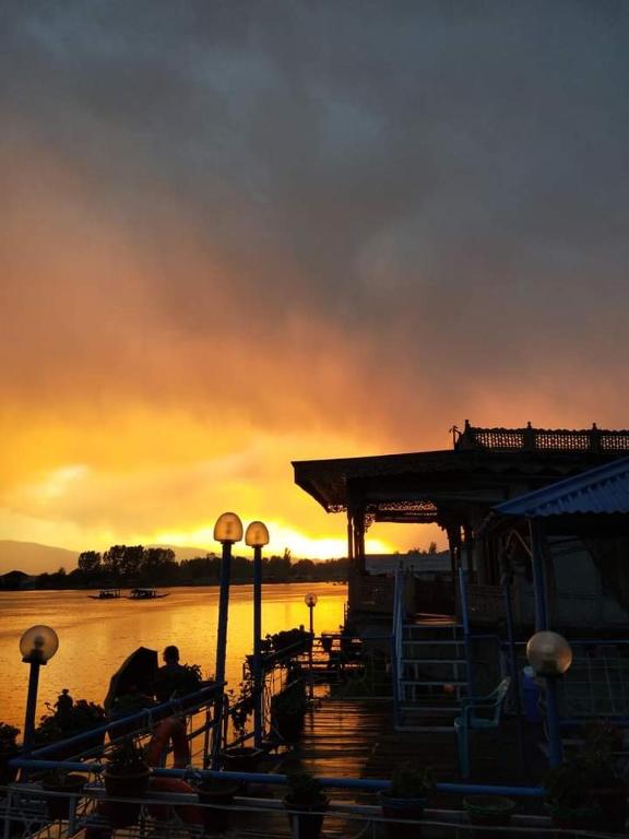 a sunset over a river with a dock with a building at Heevan in Srinagar