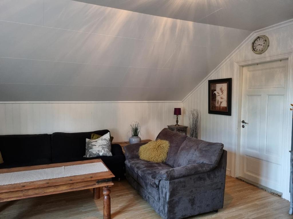 a living room with a couch and a clock on the wall at Loftsleilighet in Vennesla
