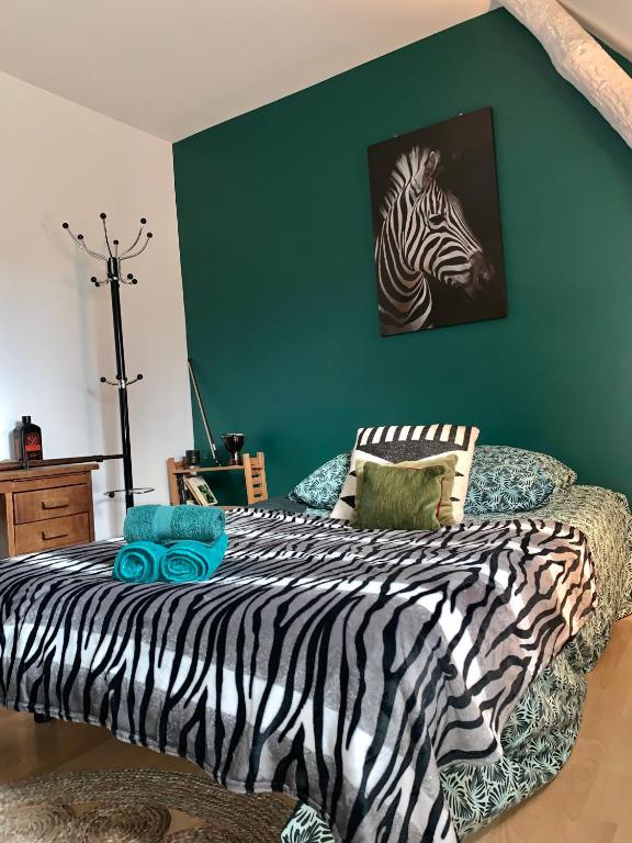 a bedroom with a zebra print bed with a green wall at Près de l'aéroport in Ossun