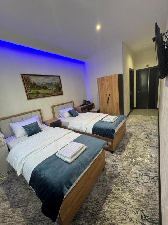 two beds in a hotel room with blue lighting at Best Guest House in Andizhan
