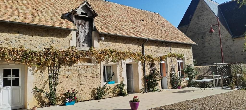 un grande edificio in pietra con l'edera che cresce sopra di LE PRESBYTERE a Rouperroux-le-Coquet