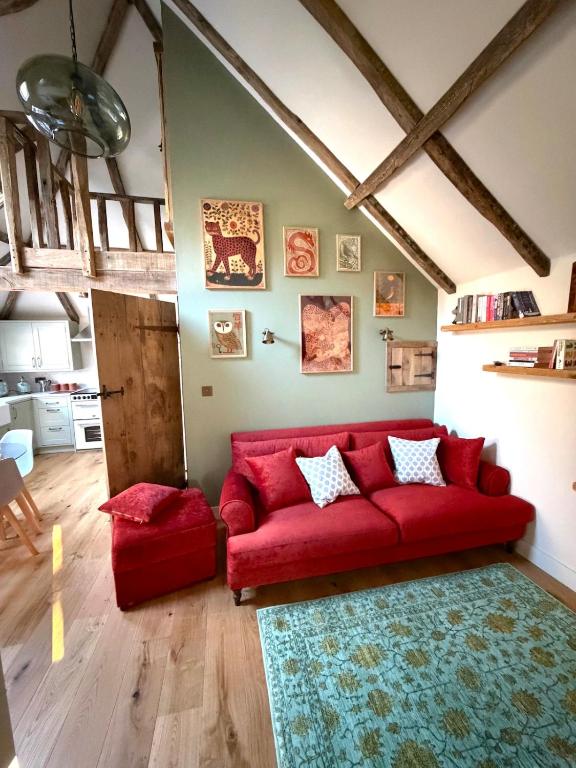 a living room with a red couch and a rug at Orchard Barn next to Bewl Reservoir, Ticehurst in Ticehurst