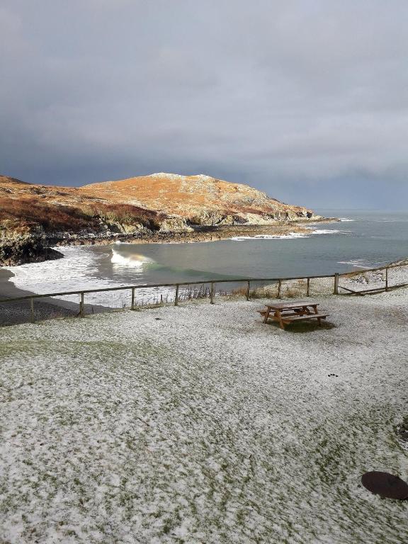 a beach with a picnic table and the ocean at Fascadale in Faskadale