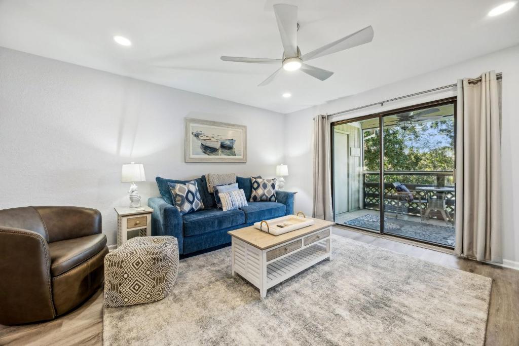 a living room with a blue couch and a ceiling fan at 4F Amelia Landings in Fernandina Beach