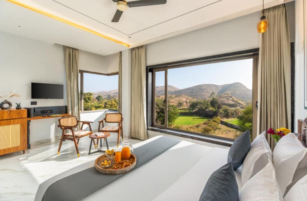 a bedroom with a bed and a large window at Shivaangan By Soma Estates in Udaipur
