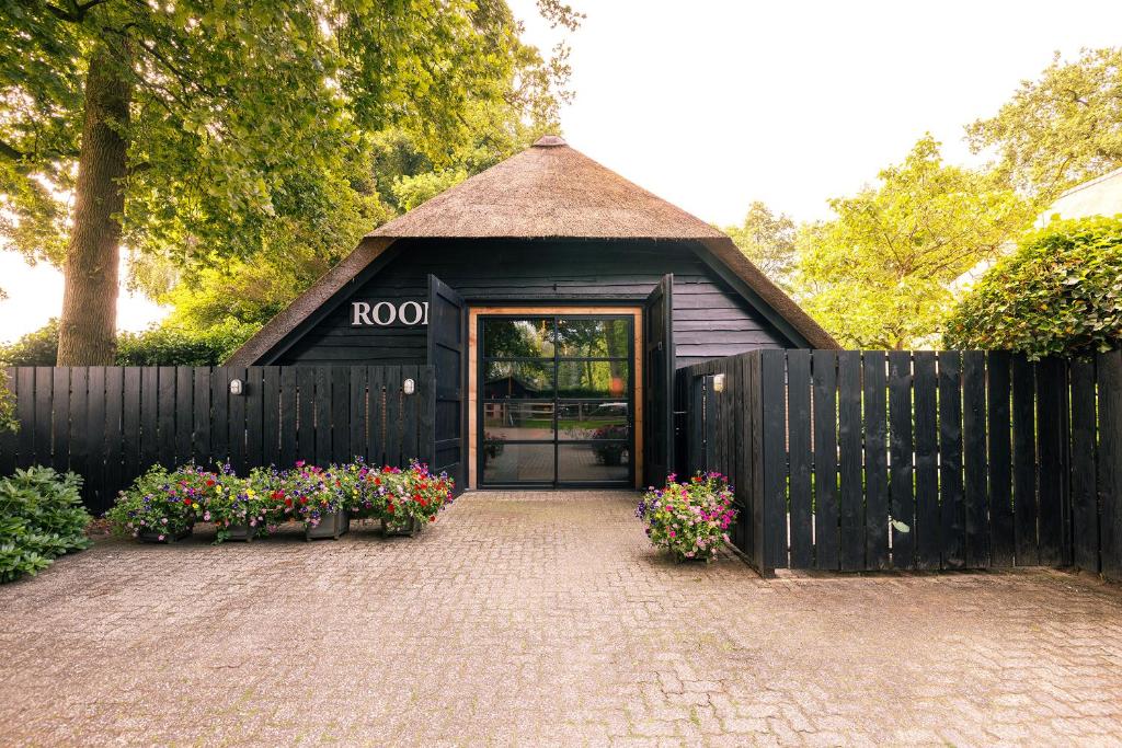 a black building with a door and some flowers at Luxe Veluwse Bosrand Suite met Jacuzzi en Zwembad in Lunteren