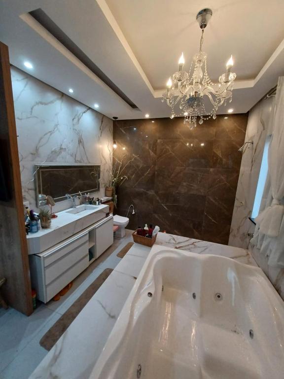 a large bathroom with a large tub and a chandelier at Loft dos sonhos cobertura in Boa Vista