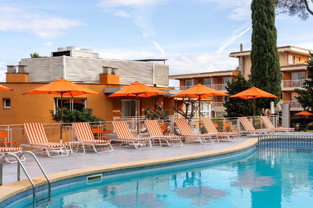 a group of chairs and umbrellas next to a pool at Hesperia Mallorca in Palma de Mallorca