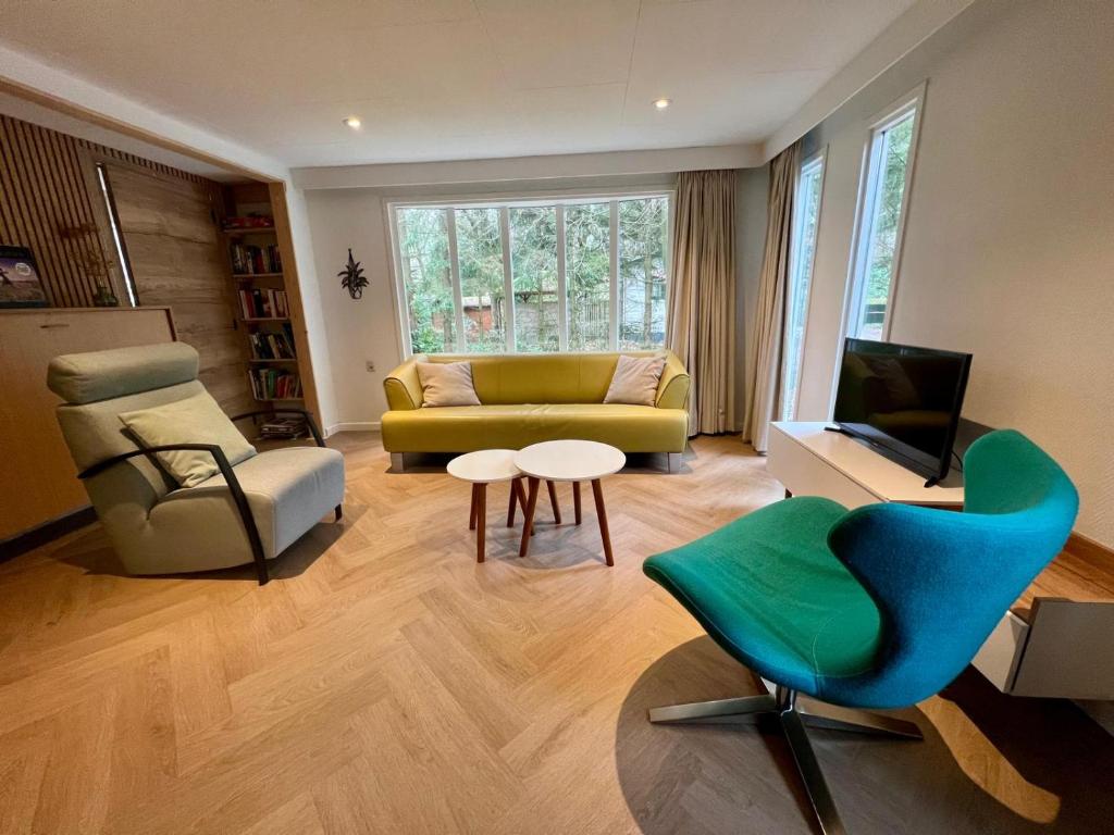 a living room with a couch and a chair at Kindvriendelijk sfeervol vakantiehuis Bosgeneugte bij zwembad op de Veluwe in Doornspijk