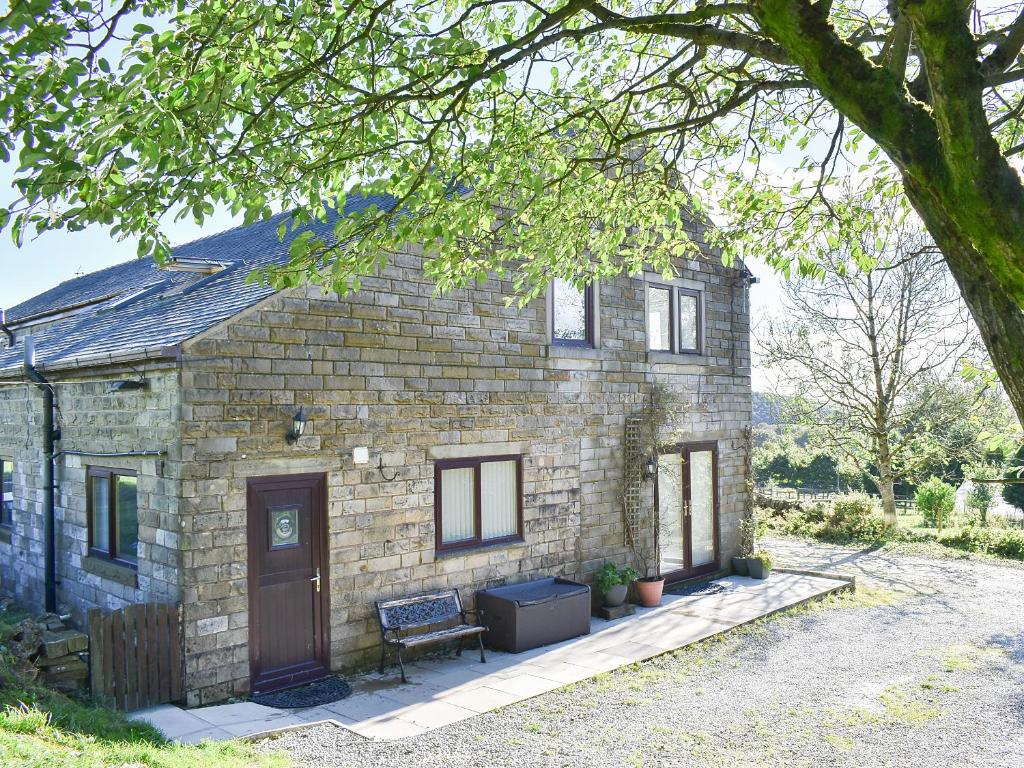 a stone house with a bench in front of it at Wesley Old Hall House in Bacup