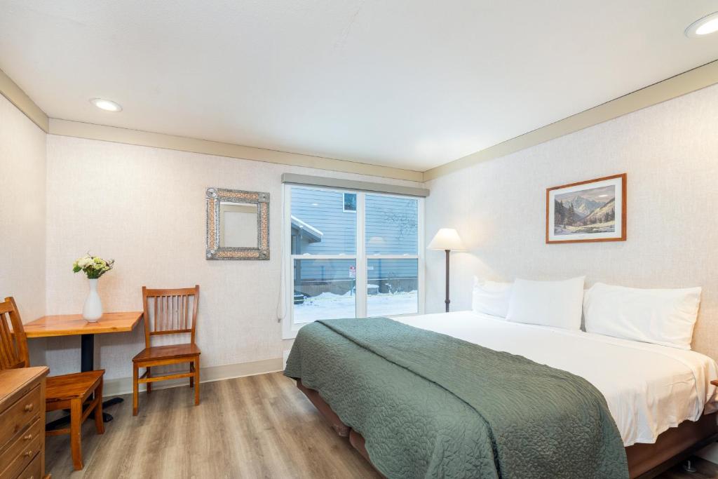 a bedroom with a bed and a desk and a window at Mountainside Inn 202 by Alpine Lodging Telluride in Telluride