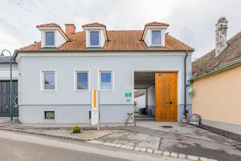 ein weißes Haus mit einer orangefarbenen Tür in einer Straße in der Unterkunft Weingut Krell in Mitterretzbach