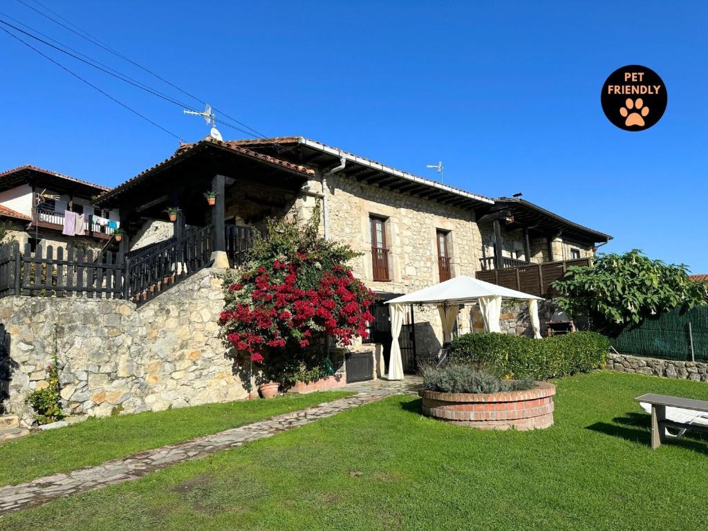 a stone house with a table and a tent in a yard at Casa Las Hortensias 1 Pendueles AT-1557-AS in Llanes