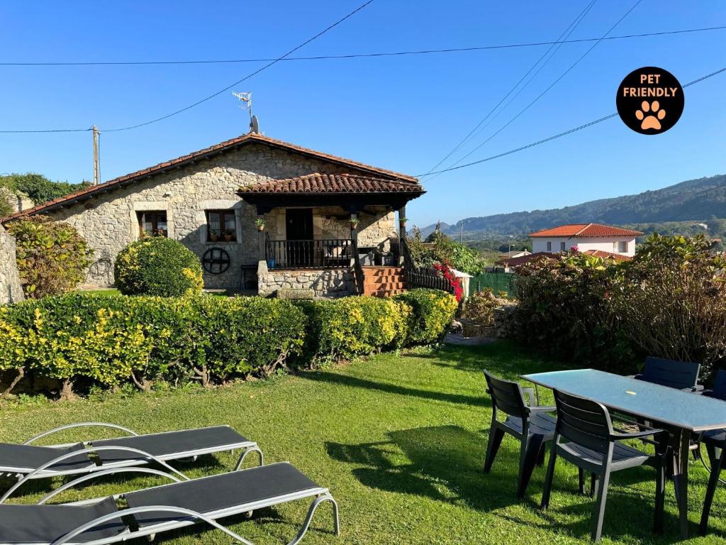 a house with a table and chairs in the yard at Casa Las Hortensias 2 Pendueles AT-1557-AS in Llanes