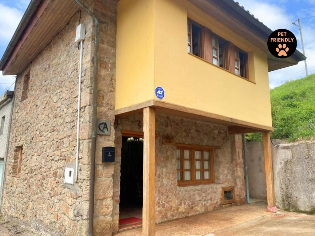 a yellow building with a door and a sign on it at Casa Rural Kiko Asturias CA-AS-4727 in Bimenes